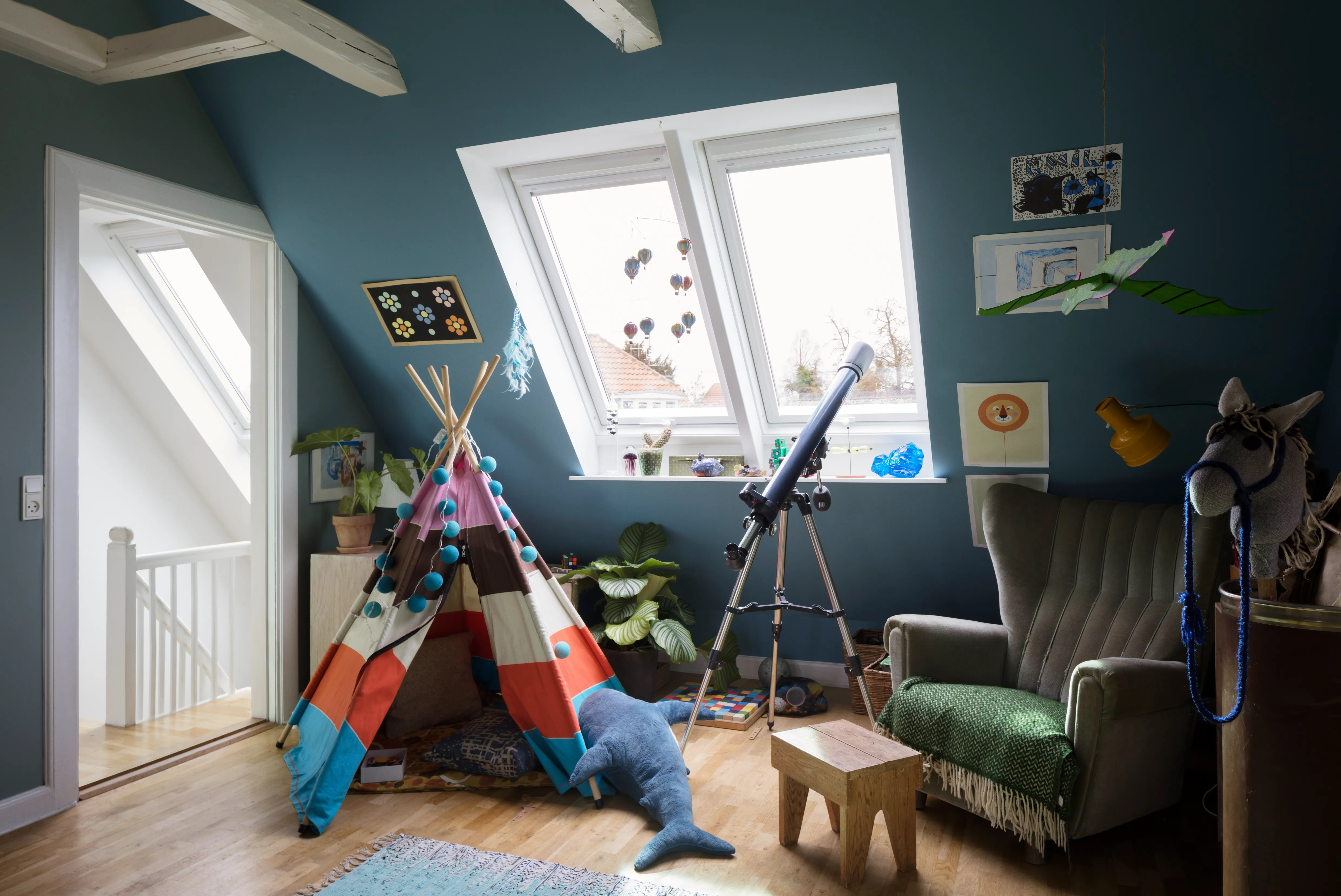 A child's room with a teepee and a chair.