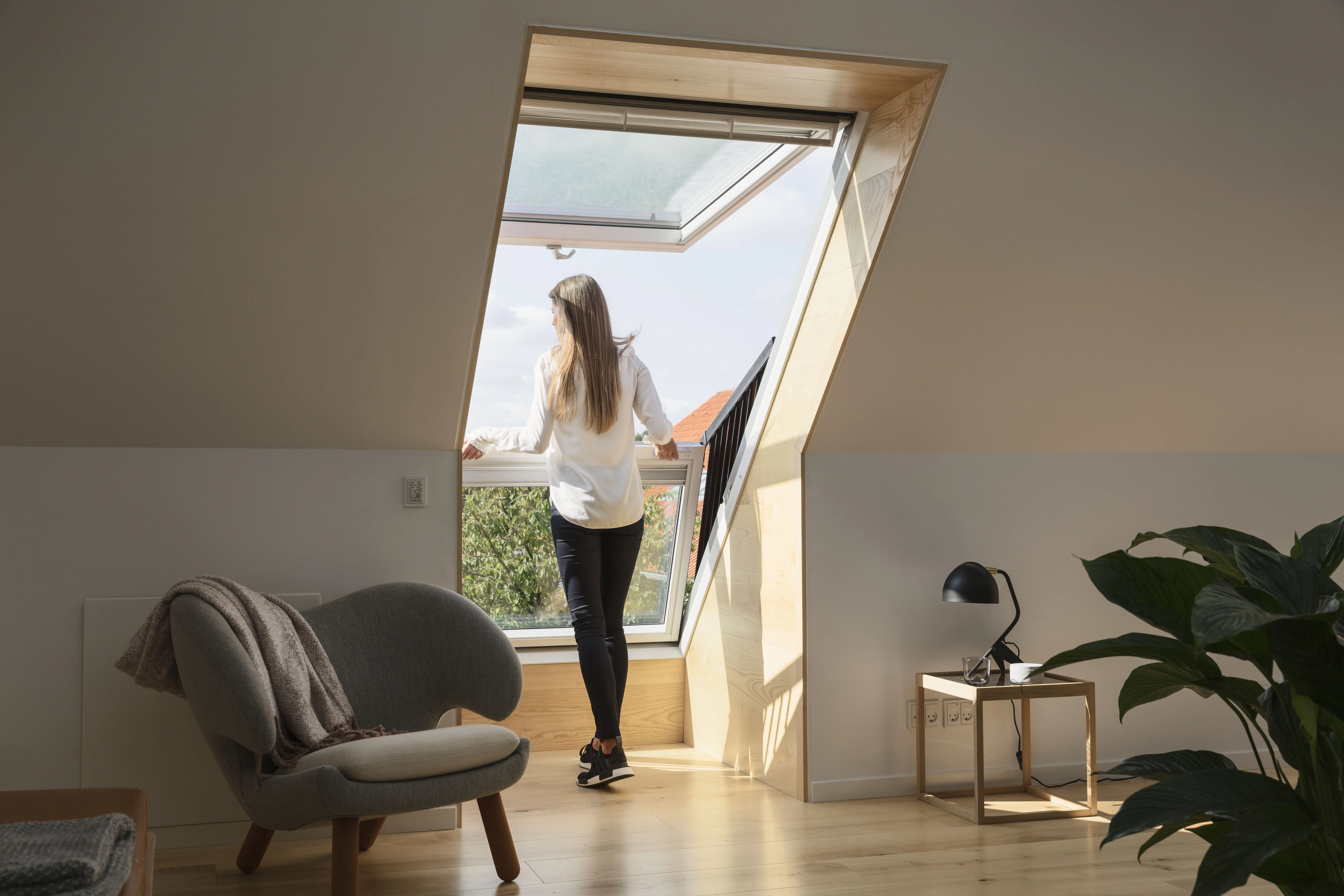 A woman standing in a room looking out a window.