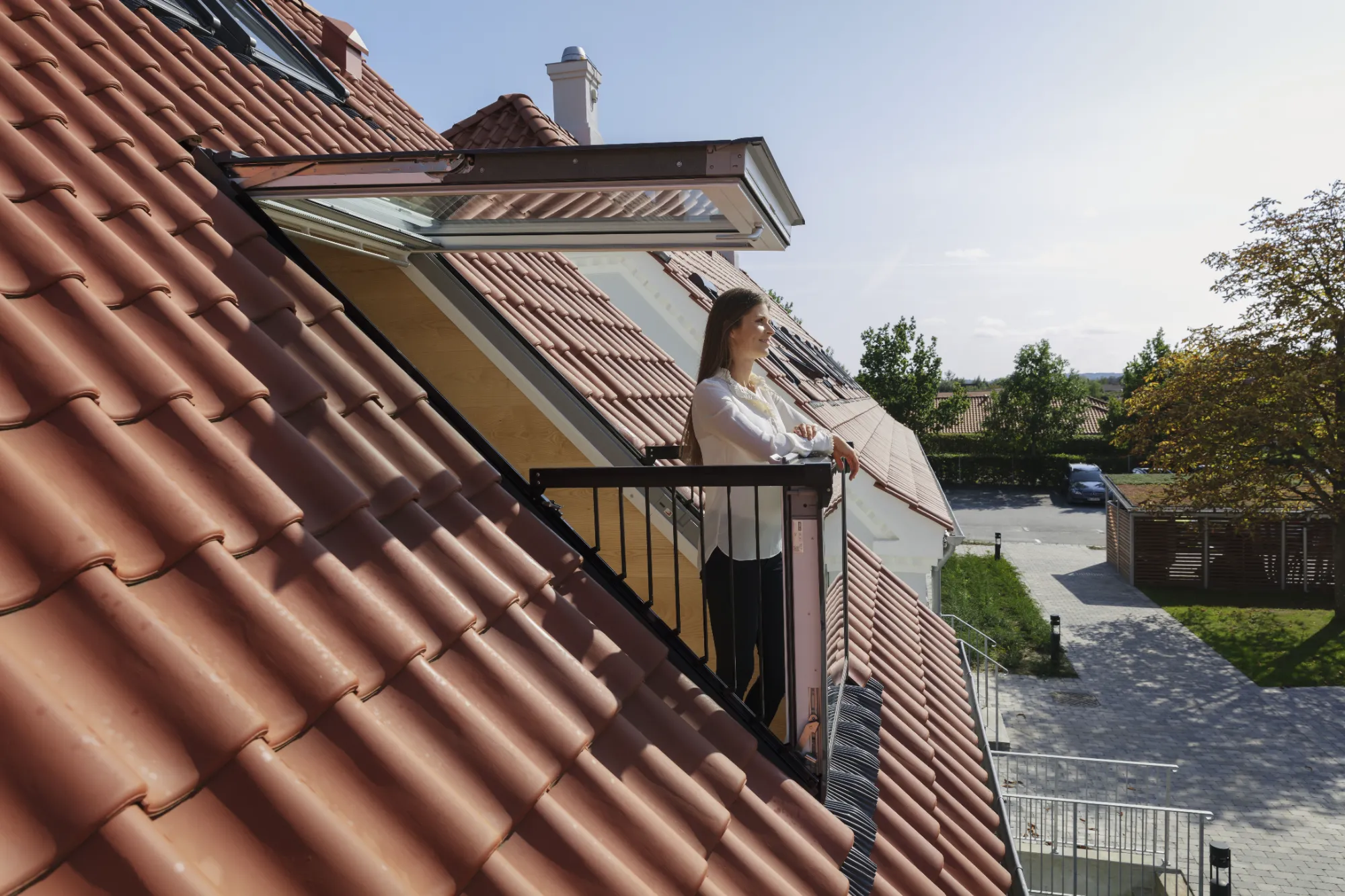 A woman standing on a balcony next to a building.