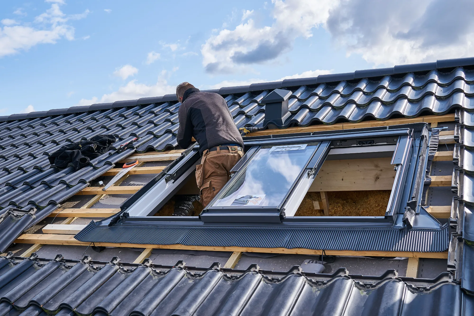 A man is working on the roof of a house.